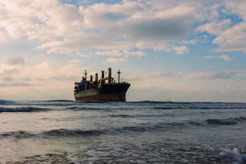 A large cargo sea ship sails on the ocean among the waves