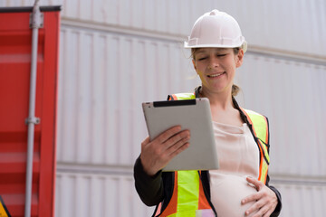 Portrait of smiling female pregnant using digital tablet and manging import and export containers...