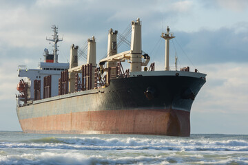 Fototapeta premium A large cargo sea ship sails on the ocean among the waves
