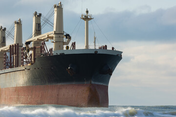 A large cargo sea ship sails on the ocean among the waves
