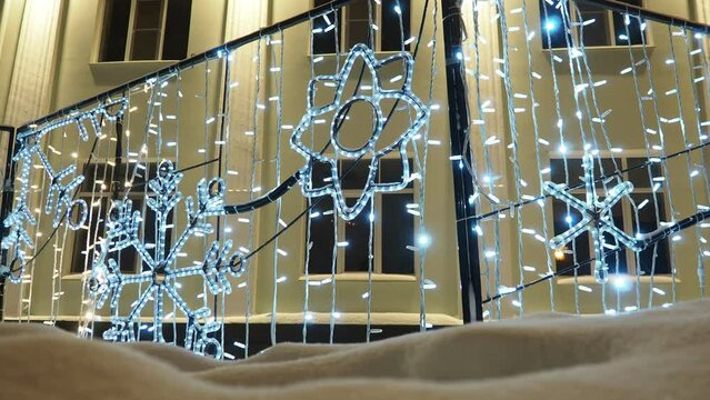 Glowing snowflakes. Festive New Year Christmas electric art installation architecture structures in snowdrift. Light decoration of city street. Winter night. Garland light bulbs shine in silver. Xmas.