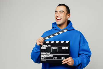 Young middle eastern man he wear blue hoody casual clothes hold in hand classic black film making clapperboard look aside isolated on plain solid white background studio portrait. Lifestyle concept.