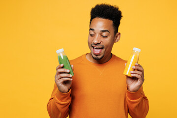 Young surprised man wear casual clothes hold show fruit juice green vegetable smoothie as detox diet isolated on plain yellow background. Proper nutrition healthy fast food unhealthy choice concept.