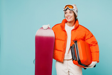 Traveler smiling woman wear padded windbreaker jacket ski goggles mask hold snowboard bag isolated...