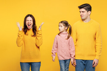 Young sad mad unhappy parents mom dad with child kid girl 7-8 years old wear pink knitted sweater casual clothes spread hands scream be stressed isolated on plain yellow background Family day concept