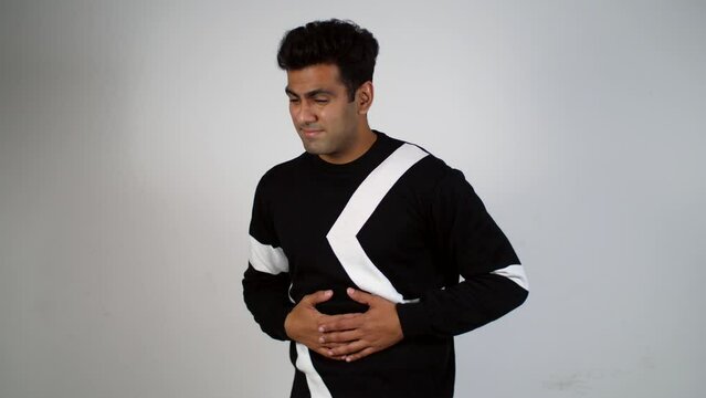Young Indian man feeling extreme stomach pain - irritated bowl syndrome  stomach ache  upset stomach  digestive issues. A tall man having severe gastric pain - acidity problem  pancreatitis  sickne...