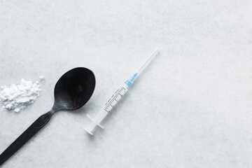 Overhead view of a syringe, black spoon, powder and rope, tools for using cocaine and heroin on a...