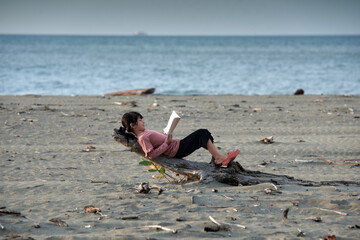 Cute Little Girls relaxing on the tropical beach and reading a book