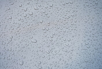 Closeup of raindrops on gray window glass texture background. . Rainy weather concept and natural condensation wallpaper.