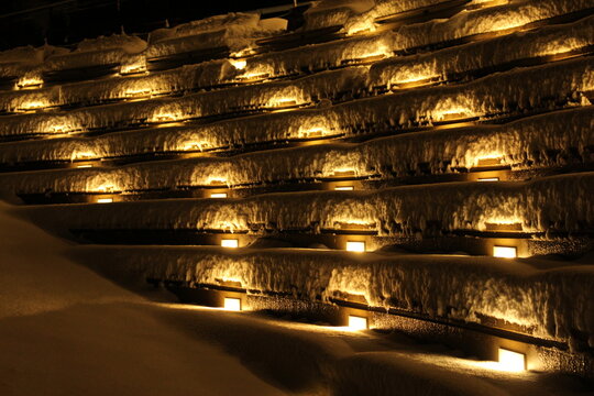 Outdoor concrete amphitheater seats for outdoor theatre venue covered in freshly fallen snow and lit up at night. Concept for snow in unusual places, snowy theatre, outdoor spaces (Vancouver, Canada)
