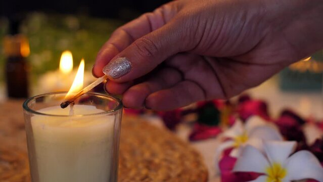 Burning scented candle -  relaxing environment  peaceful time  lightening candle  spa essentials  flowers  essential oil bottles  facial serum. A beauty salon with decorated table and aromatic cand...