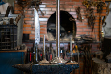 The blade and blanks for forging a knife on an anvil against the background of a blast furnace in a...