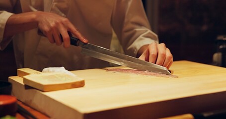 Hands, food and chef cutting sushi in restaurant for traditional Japanese cuisine or dish closeup. Kitchen, cooking seafood for preparation and person working with gourmet meal recipe ingredients