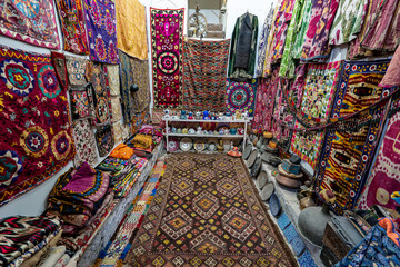 Variety of gorgeous oriental carpets in traditional carpet store in Middle East. Pile of beautiful handmade carpets on the traditional Middle East market bazaar. uzbek colorful carpets close-up - obrazy, fototapety, plakaty