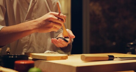 Hands, food and chef cooking sushi in restaurant for traditional Japanese cuisine or dish closeup....
