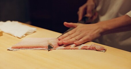 Hands, food and sushi chef cutting fish in restaurant for traditional Japanese cuisine or dish...