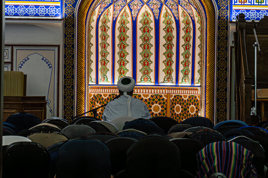 People in a Mosque. Muslims kneeling and bowing down while offering prayers during the Muslim festival of Eid. imam reads a prayer