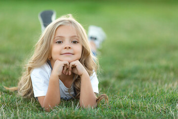 Happy little girl lying on grass and smiling. Perfect for innocence and joy of childhood concept....