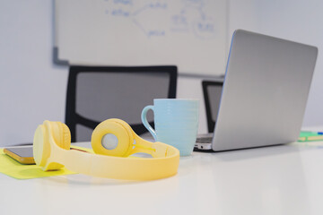 A modern work desk setup with a laptop and yellow headphones, symbolizing a blend of technology and style in a creative workspace. 