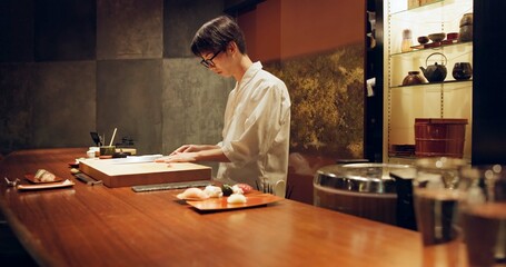 Chef, cooking and sushi in kitchen of restaurant for traditional food, cuisine or gourmet dish. Luxury, catering and salmon with Japanese man cook cutting fish for seafood meal ingredients or recipe