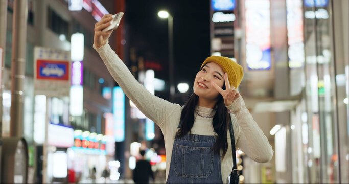 Peace, hands and selfie by Japanese woman in a city for travel, adventure or journey outdoor. V sign, emoji or happy lady influencer in Japan for content creation, blog or social media live streaming