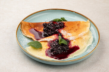 Portion of sweet crepe blini pancakes with jam and berries