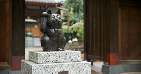 Maneki neko, statue and Japanese or traditional temple at woods garden for respect, worship or spirituality. Sculpture, lucky cat and outdoor or traveling adventure in Tokyo, Gotokuji and fortune