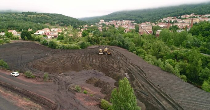 Heavy truck unloading soil next to a bulldozer, aerial view