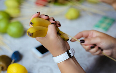 Making of bouquet of fruits, gift for lover.  Hand holding a banana for a beautiful fruit bouquet. 