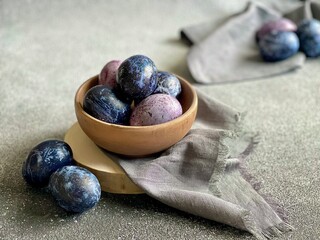 Beautiful blue and purple Easter eggs in a wooden bowl on a gray background. Easter eggs painted in a solution of hibiscus flowers. Easter egg composition . 