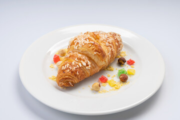 Breakfast. Croissant, seeds and dried fruits on a white plate and a white background