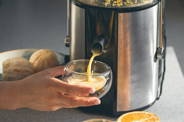 A woman preparing fresh orange juice for breakfast in kitchen.