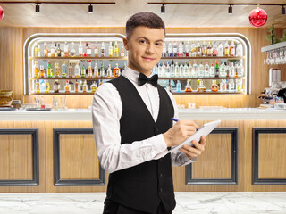 Young male server with a bow tie writing down an order