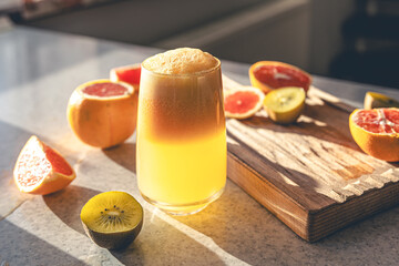 Freshly squeezed juice in a glass and fresh fruit on the kitchen table.