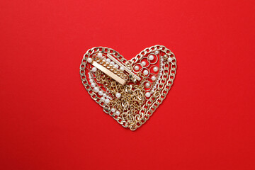 Heart made of jewelry on a red background.