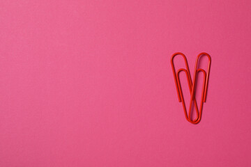 Heart from paper clips, on a red background.
