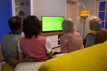 Family watching TV. Green screen. Two couples, an elderly and a middle-aged couple, are sitting on...