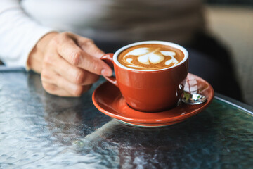 Human hand holding hot latte coffee art latte coffee cup A coffee drink made from espresso and...