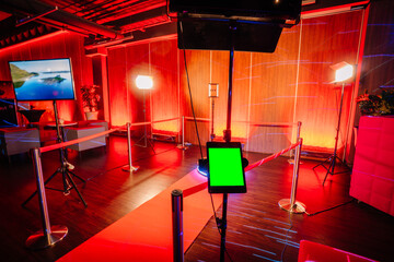 360 spinner photo booth setup with a red carpet, lighting equipment, and a screen in a red-lit...