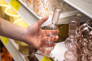 Glass vase in a female hand in a home goods store.