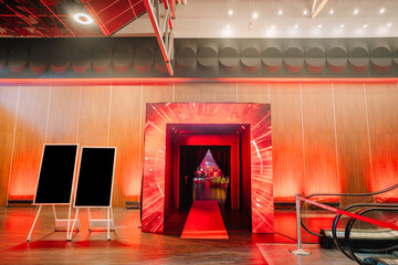  entrance with dynamic red lighting effects leading to an event space, flanked by blank signage...