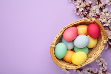 Happy Easter. Colorful Easter eggs with cherry blossoms on purple background. Greeting card or banner.