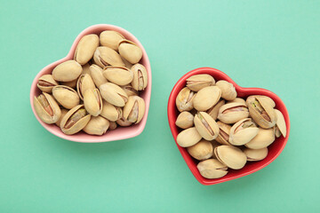 Bowls with pistachios on mint background.