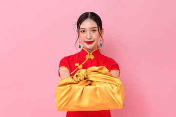 Chinese new year portrait of elegant Asian woman in traditional cheongsam dress giving golden gift...