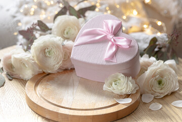 Composition with a pink heart-shaped gift box and flowers.