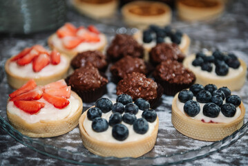 Set of tasty sweet tartlets with fresh berries. Tarts closeup. Candy bar for the wedding. Standing festive table with desserts, and cupcakes. Beautiful and tasty for the event in a restaurant.