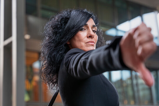 businesswoman with serious look pointing finger down looking at camera outdoors