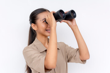 A cheerful young Filipino woman with binoculars, looking into the distance with a smile.