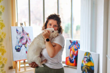 the artist with a white small dog East East Terrier examines her painting