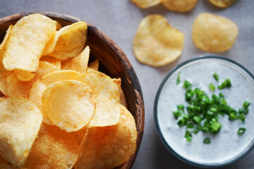 Potato chips with sauce with herbs on a gray background